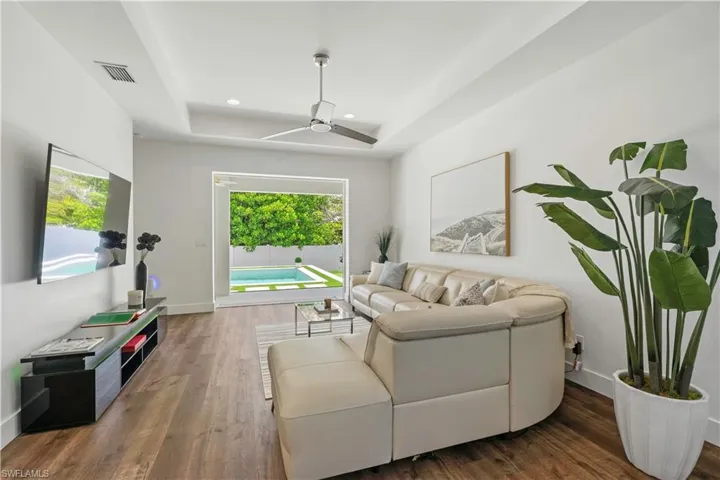 Living room featuring dark wood finished floors, a raised ceiling, ceiling fan, and recessed lighting