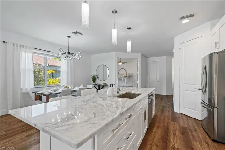 Kitchen featuring white cabinets, light stone counters, stainless steel appliances, ceiling fan, and pendant lighting
