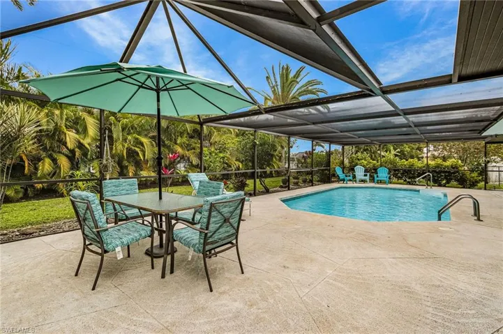 Swimming pool featuring glass enclosure, a patio, outdoor dining area, and a sunroom