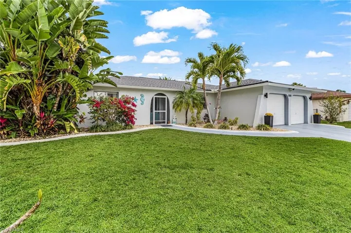 Ranch-style home with stucco siding, an attached garage, and a front yard