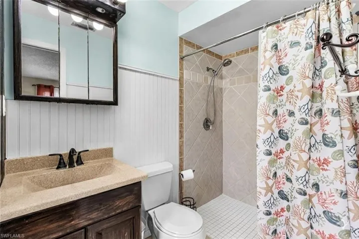 Full bathroom with vanity, a stall shower, and a wainscoted wall