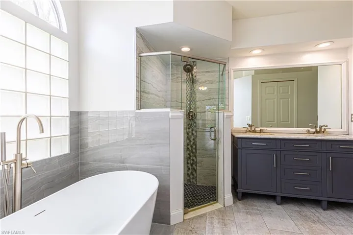 Primary Bathroom featuring shower with separate soaking bathtub and double vanity