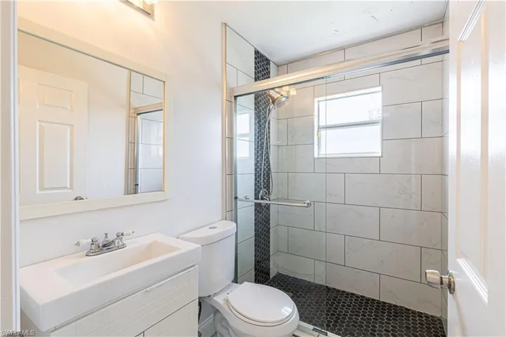 Bathroom featuring vanity, toilet, and an enclosed shower