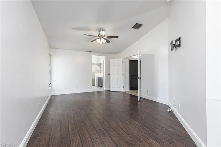 Primary Bedroom featuring dark floors, ensuite bathroom, and ceiling fan