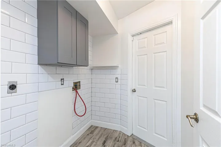 Laundry area with hookup for a washing machine, cabinets, tile walls, and electric dryer hookup