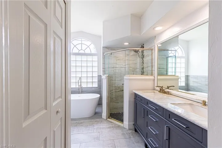 Primary Bathroom featuring lots of natural light, double vanity, walk in shower and soaking tub.