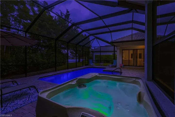View of pool with a patio, a lanai, and a hot tub
