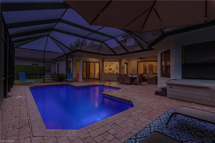 View of swimming pool with glass enclosure, a patio area, and an outdoor hangout area