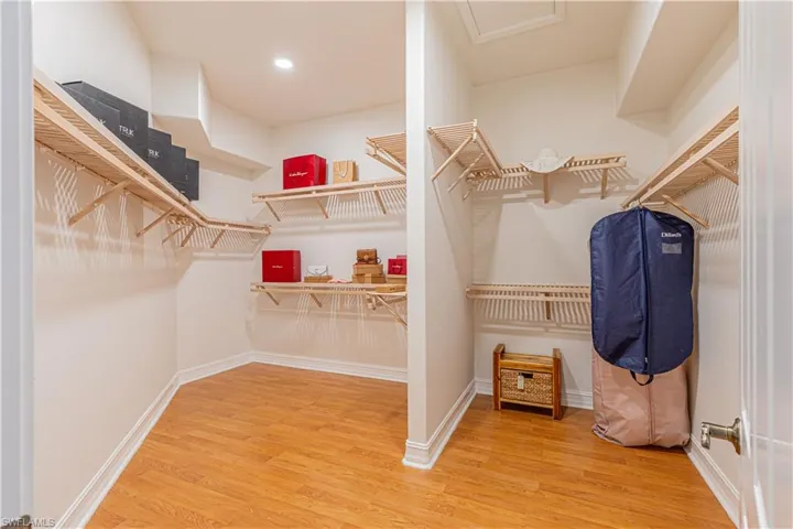 Walk in closet with hardwood / wood-style floors