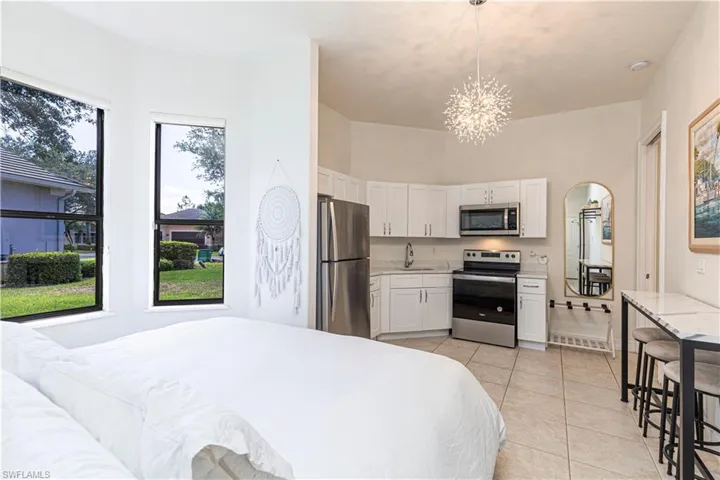 Tiled bedroom with sink, an inviting chandelier, and stainless steel fridge