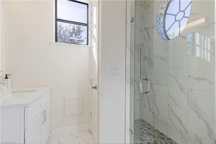 Bathroom with tile patterned floors, a shower with door, and vanity