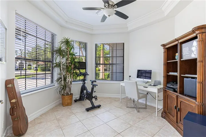 Tiled office with ceiling fan, crown molding, and a tray ceiling