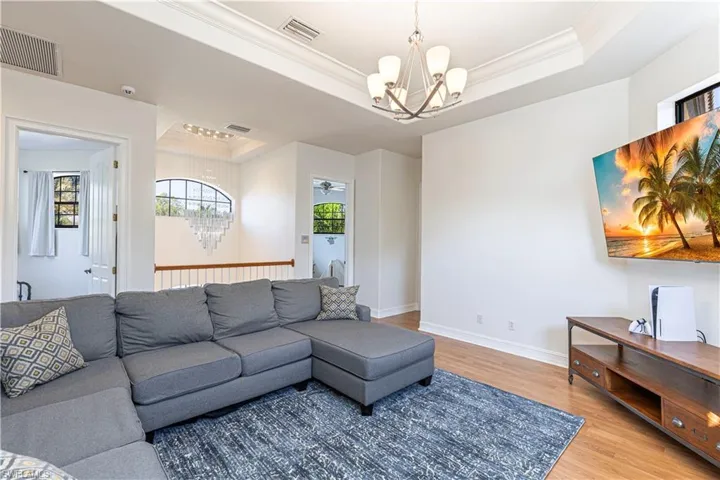 Living room featuring a raised ceiling, hardwood / wood-style flooring, and a chandelier