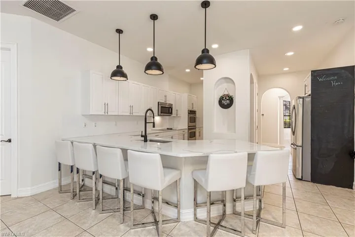 Kitchen featuring sink, white cabinetry, light tile patterned floors, stainless steel appliances, and kitchen peninsula