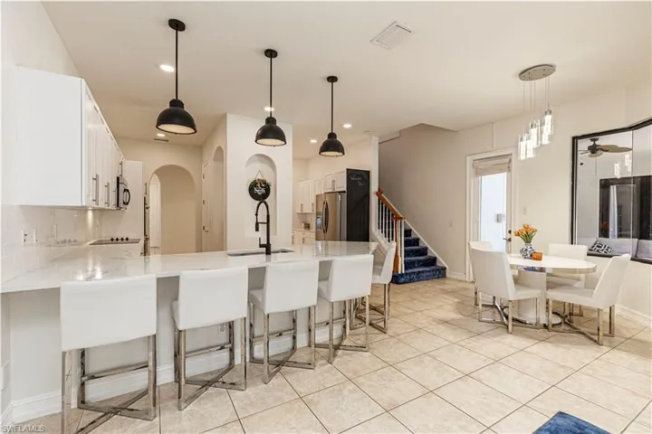 Kitchen with backsplash, stainless steel appliances, white cabinetry, sink, and light tile patterned floors