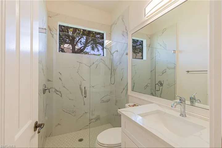 Bathroom with toilet, walk in shower, and vanity
