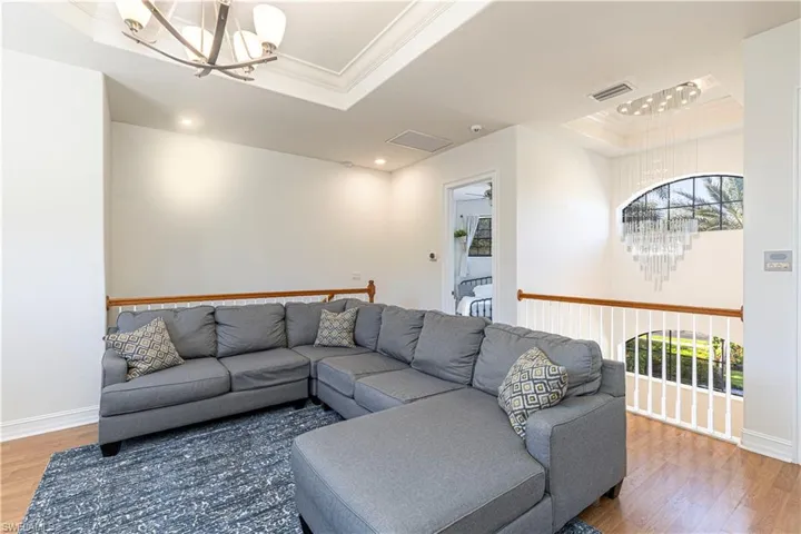 Living room with a notable chandelier, a raised ceiling, and wood-type flooring