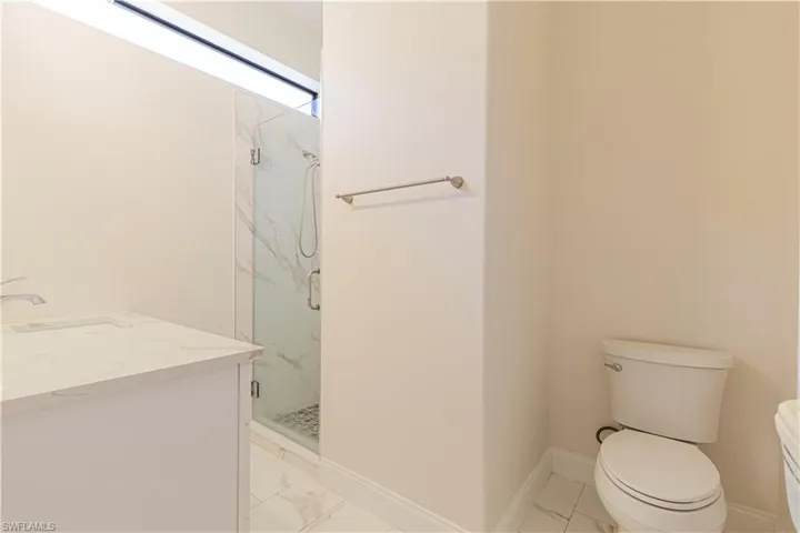 Bathroom with tile patterned floors, a shower with door, vanity, and toilet