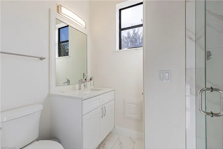 Bathroom featuring tile patterned flooring, toilet, walk in shower, and vanity