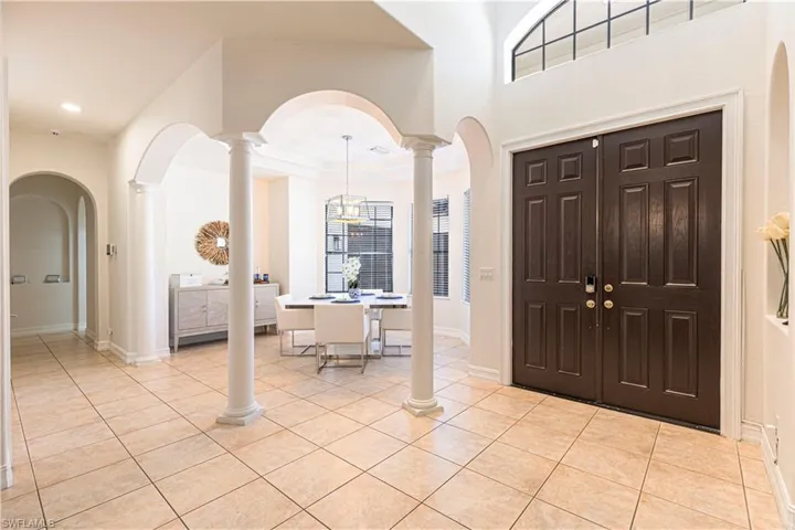 Tiled entryway featuring crown molding and ornate columns