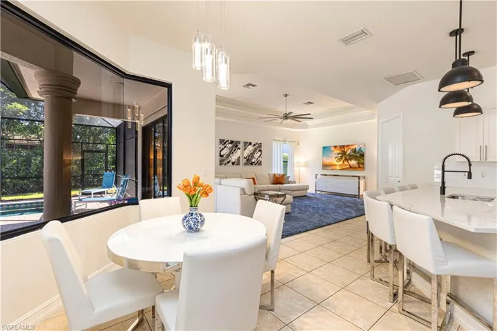 Tiled dining area with sink, a raised ceiling, plenty of natural light, and ceiling fan