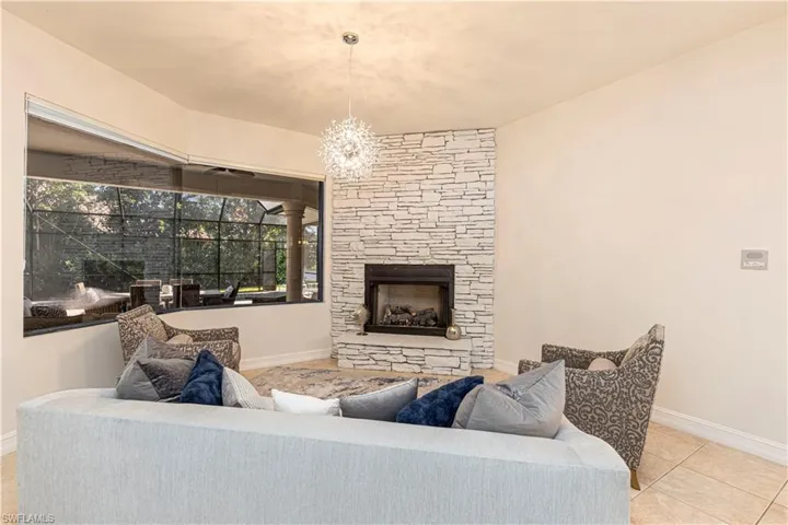 Living room with a fireplace, light tile patterned flooring, and an inviting chandelier