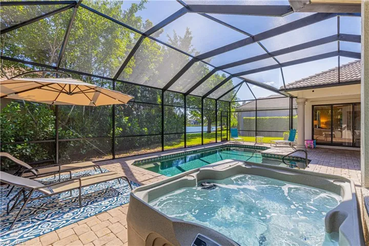 View of swimming pool featuring glass enclosure and a patio