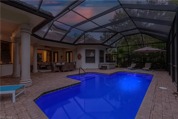 Pool at dusk featuring glass enclosure, an outdoor living space, a patio area, and ceiling fan