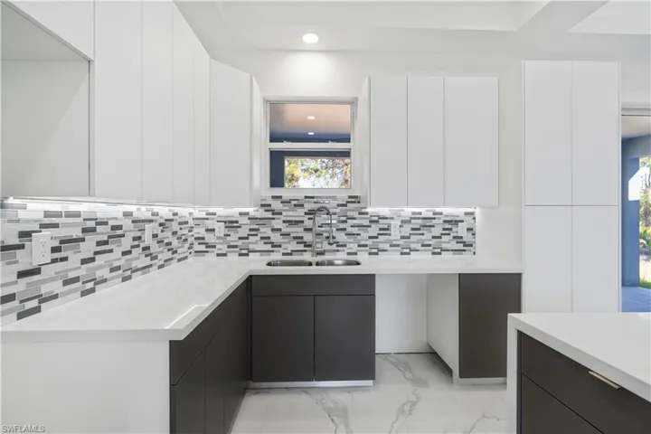 Dual tone kitchen featuring modern cabinets, light stone counters, dual tone cabinetry, light marble finish floors, and recessed lighting