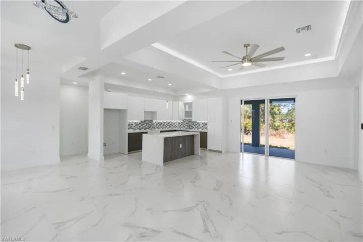 Dual tone kitchen with open floor plan, a center island, modern cabinets, ceiling fan, and two tone color scheme