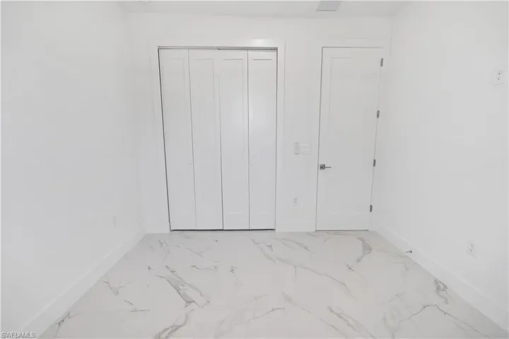 Unfurnished bedroom with light marble finish flooring and a closet