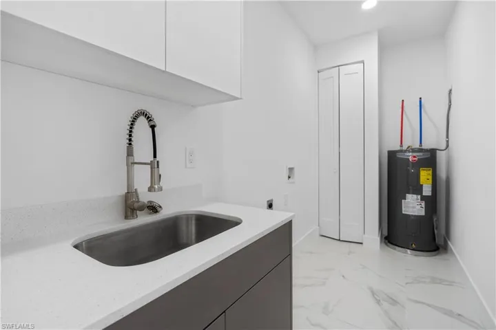 Laundry area with hookup for an electric dryer, electric water heater, washer hookup, light marble finish flooring, and recessed lighting