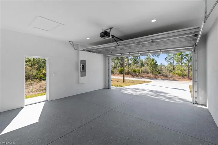 Garage with electric panel, a garage door opener, and recessed lighting