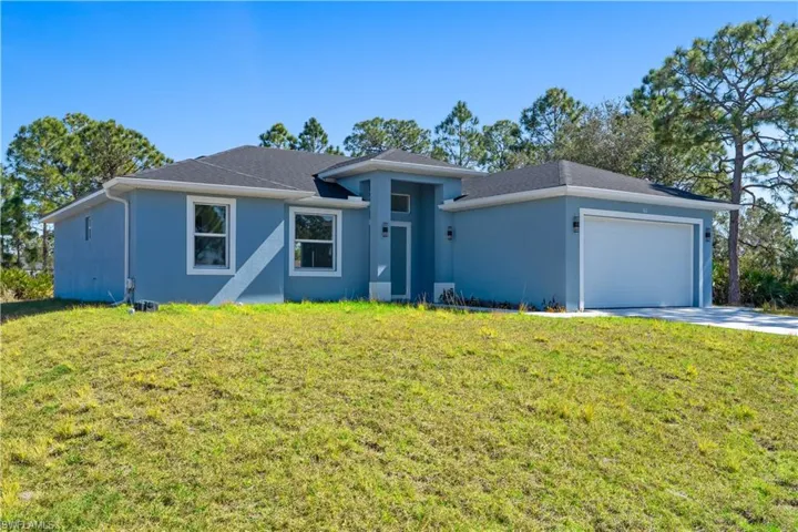 View of front of home featuring a garage, a front lawn, stucco siding, and driveway