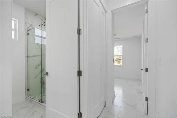 Bathroom with healthy amount of natural light, light marble finish floors, and a marble finish shower