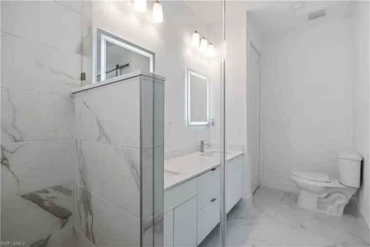 Bathroom featuring double vanity and light marble finish floors