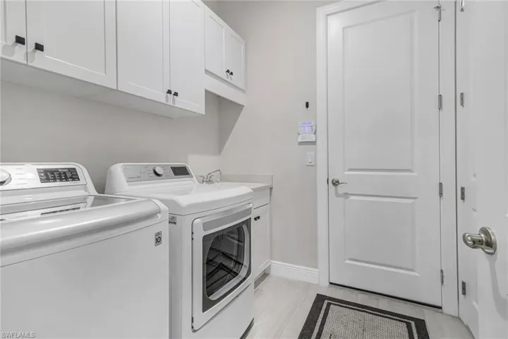 Laundry area featuring washer and clothes dryer, cabinet space, baseboards, and a sink