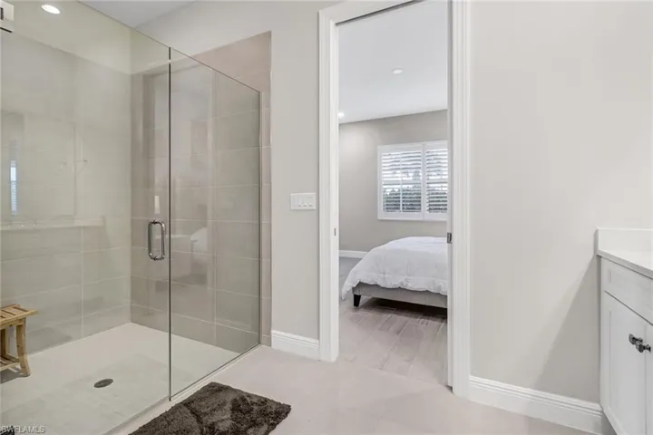 Ensuite bathroom featuring a stall shower, recessed lighting, connected bathroom, baseboards, and vanity