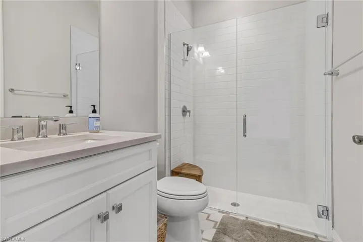 Bathroom featuring a stall shower, toilet, and vanity