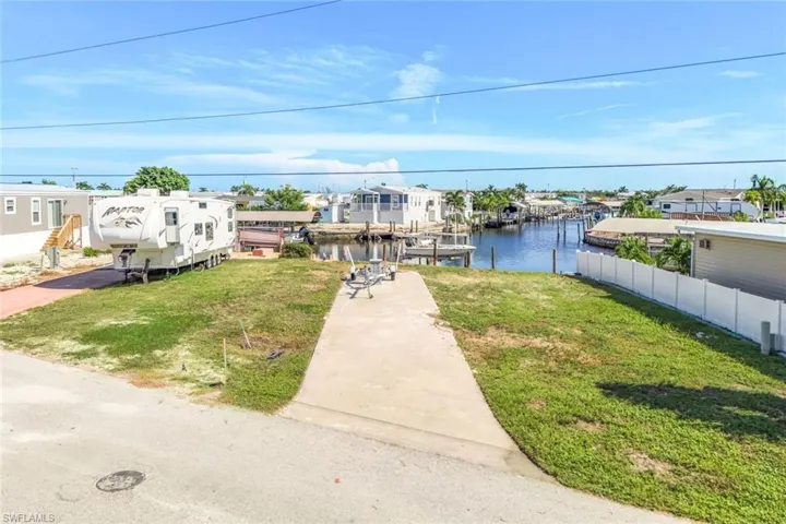 View of front of house with a front lawn, a water view, and a boat dock