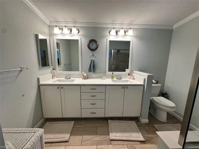 Bathroom featuring vanity, crown molding, toilet, and a textured ceiling