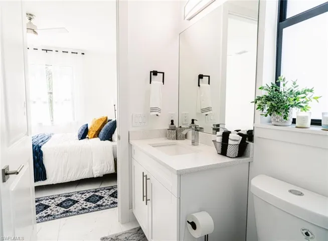 Contemporary bathroom featuring a single vanity with quartz countertop, white cabinetry with silver-tone hardware, and an undermount sink with a chrome faucet