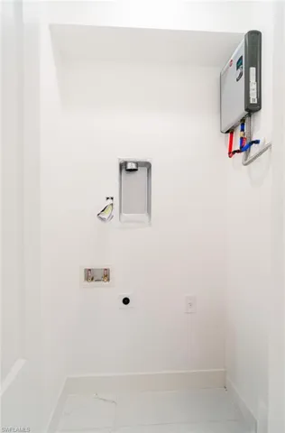 Dedicated utility space featuring a tankless water heater, white tile flooring, and clean white walls