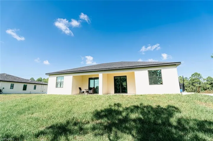 Rear exterior featuring a covered patio, sliding glass doors, and multiple windows