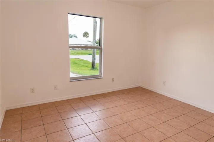 Empty room featuring light tile patterned floors and baseboards
