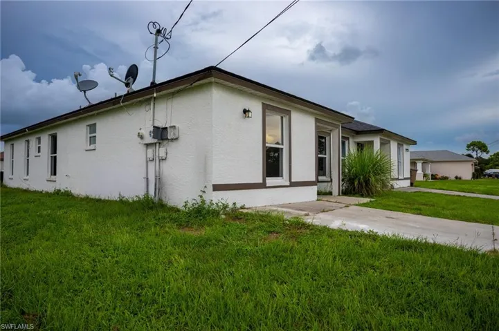 View of side of property featuring a yard and stucco siding