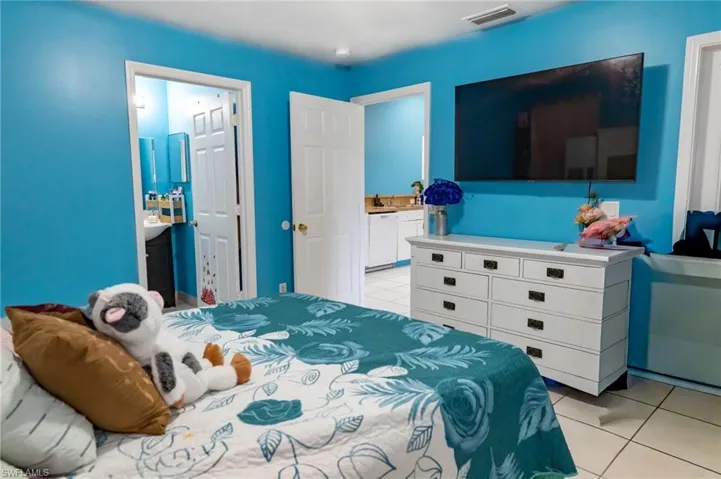 Bedroom featuring light tile patterned floors and connected bathroom
