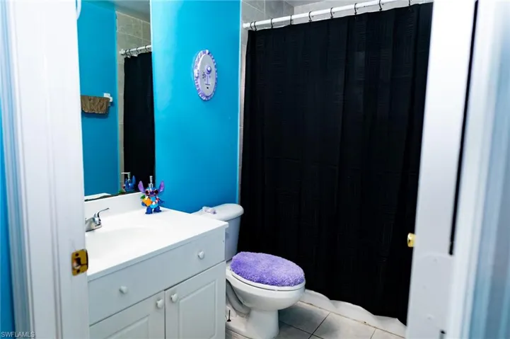 Full bath featuring vanity, light tile patterned floors, and curtained shower