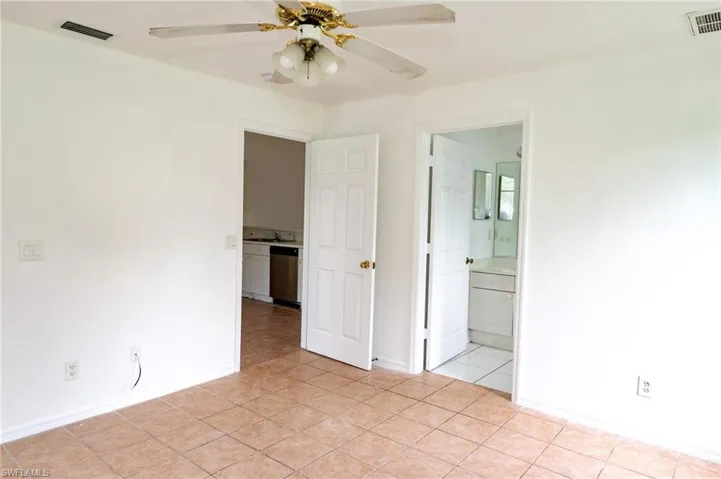 Unfurnished bedroom featuring light tile patterned floors, ceiling fan, and ensuite bathroom