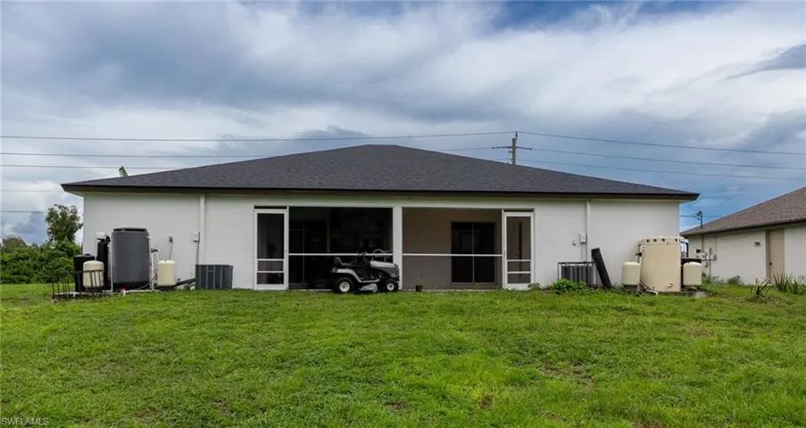 Rear view of property with a lawn, a sunroom, stucco siding, and roof with shingles